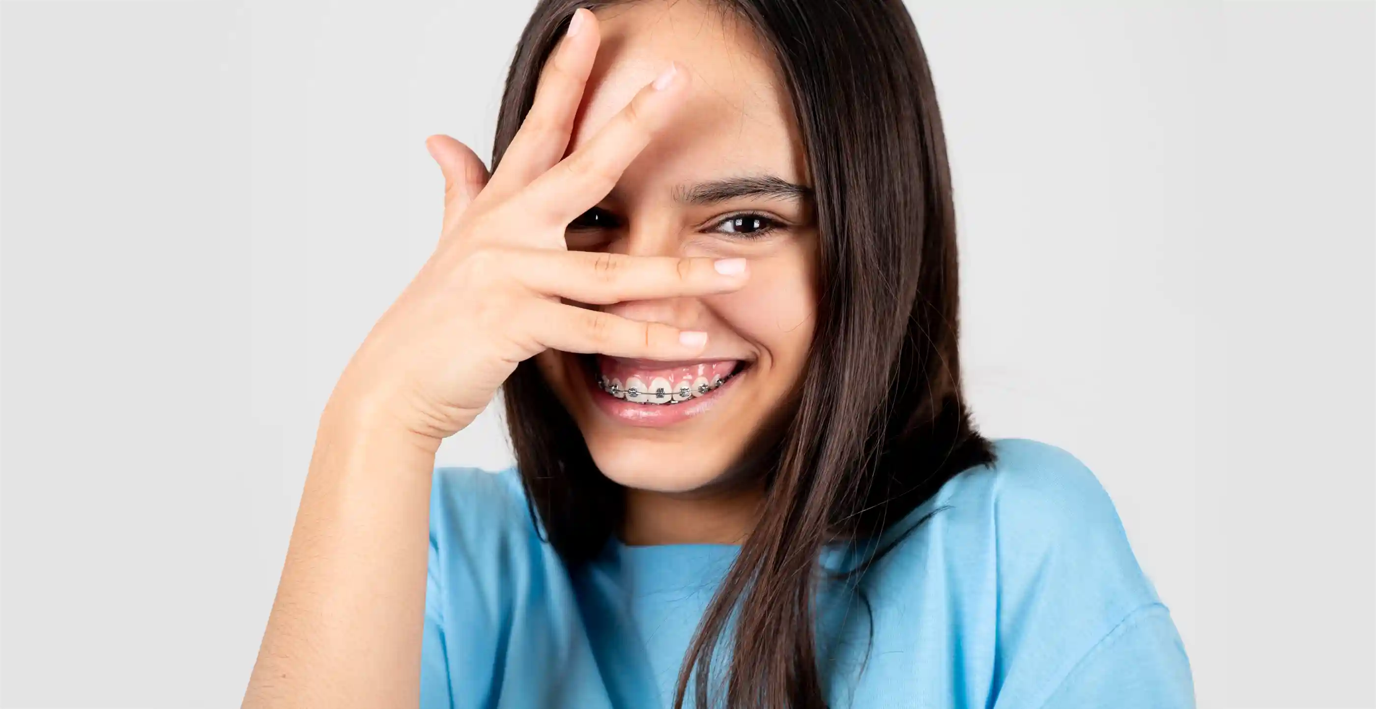 Porträt eines beschämten und lustigen Teenagers, der eine Zahnspange zeigt.